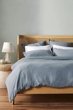 the bed is made with blue linens and pillows, along with two lamps on either side