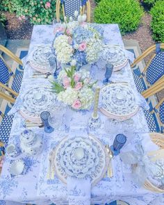 the table is set with blue and white plates, silverware, and floral centerpieces