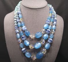 *Description: This is a beautiful and unique mid-century beaded necklace with gorgeous beads in shades of blue and clear from the 1950s. This necklace has faceted clear crystal aurora borealis beads, blue moonglow Lucite beads, light and dark blue glass art beads, and clear turquoise art beads on three strands. There are blue faux pearls which have some damage on their coating. The remainder of the beads are so exquisite that the faux pearls blend in. There is a beautiful 20mm blue glass box cla Vintage Glass Jewelry With Gemstone Beads, Vintage Blue Glass Beaded Necklaces, Blue Beaded Retro Jewelry, Retro Blue Beaded Jewelry, Vintage Blue Beaded Necklace, Vintage Blue Round Beaded Necklace, Vintage Blue Gemstone Bead Necklace, Turquoise Art, Beaded Jewelry Necklaces