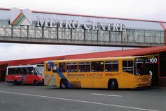 two buses are parked in front of the metro center sign and overpass above them