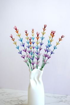 a white vase filled with colorful flowers on top of a table