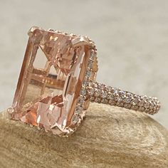 a fancy pink diamond ring sitting on top of a rock