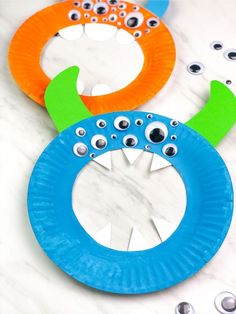 three paper plates with googly eyes and monster faces on them sitting on a marble surface