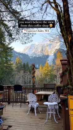 there are chairs and tables on the deck in front of mountains with trees around them