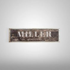 a wooden sign that says miller homestead on the side of a wall in front of a white background