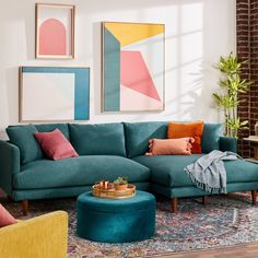 a living room with blue couches and colorful art on the wall behind it,