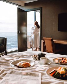 a woman in a bathrobe stands at the door to a room with a view