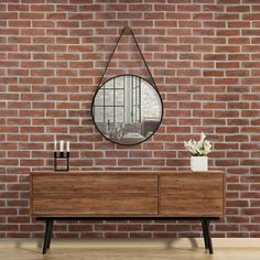 a wooden dresser sitting next to a brick wall with a round mirror on top of it