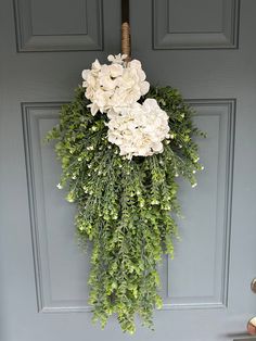 a wreath with white flowers hanging on a door