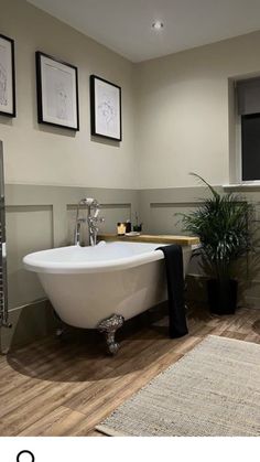 a bath tub sitting next to a toilet in a bathroom under three pictures on the wall