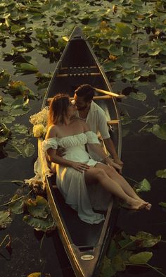 a man and woman are sitting in a row boat on the water with lily pads