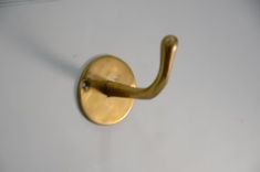 a close up of a brass hook on a white wall