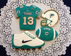 cookies decorated to look like sports uniforms and shoes are on a doily with lace