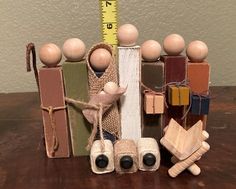 a group of wooden toys sitting on top of a table next to a measuring tape