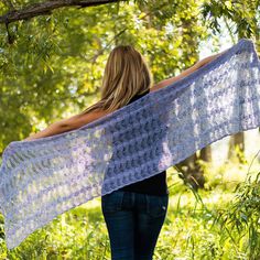 a woman standing under a tree holding a shawl