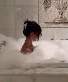 a woman sitting in a bathtub filled with foam