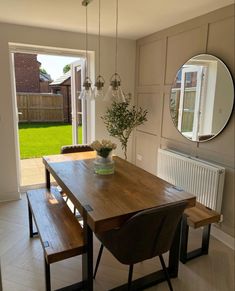 a wooden table with two benches and a mirror on the wall above it in a dining room