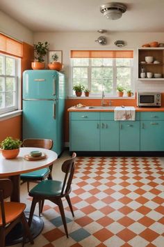 an orange and white checkered floor in a kitchen with teal cabinets, blue refrigerator, and brown chairs