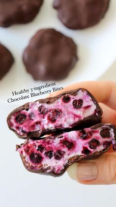 someone is holding some chocolate covered cookies with blueberries on them and the other half has been cut in half