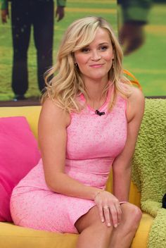 a woman in a pink dress sitting on a yellow couch