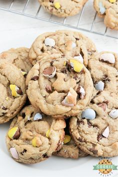 a pile of chocolate chip cookies sitting on top of a white plate next to a cooling rack