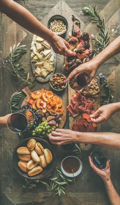 several people are gathered around a table with food and drinks on it, top view