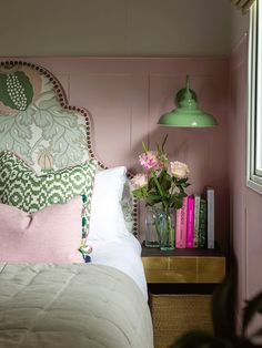 a bedroom with pink walls and white bedding, green lampshade over the headboard