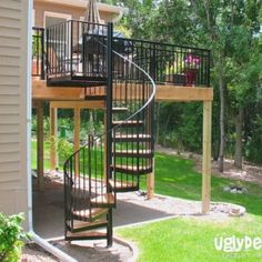 there is a spiral staircase going up the side of this house in the yard,