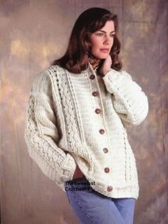 a woman wearing a sweater and jeans posing for the camera with her hand on her chin