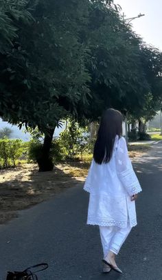 a woman is walking down the street with her dog in tow, and she has long black hair