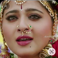 a close up of a woman with makeup and jewelry on her face, looking at the camera