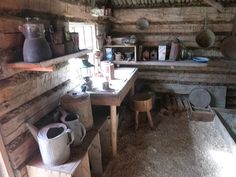 an old log cabin with wooden walls and shelves filled with pots, pans and other items