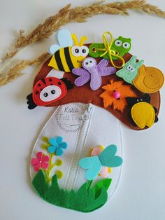 an assortment of felt animals and bugs on a white surface with some dried grass in the foreground