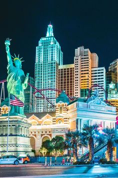 the statue of liberty is lit up at night in las vegas, nv with other tall buildings behind it