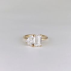 an engagement ring with two pear shaped diamonds on the side, set in yellow gold