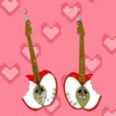 an image of two apple shaped earrings on pink background