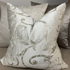 two silver pillows sitting on top of a couch