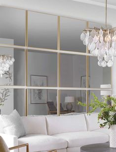 a living room filled with white furniture and lots of glass balls hanging from the ceiling