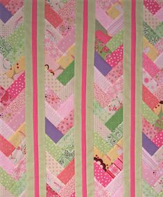 a quilted wall hanging with pink and green strips