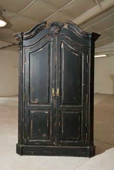 an old black armoire in a garage