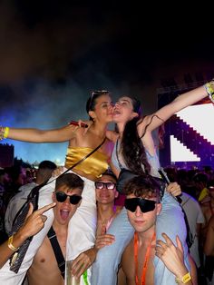 a group of people standing next to each other at a music festival with their arms in the air