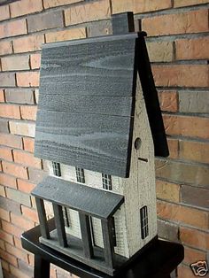 a model house sitting on top of a wooden stool in front of a brick wall