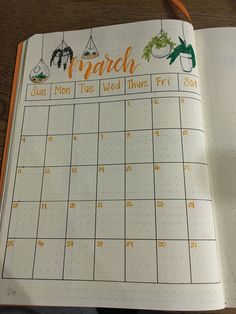 an open planner with the words march written in orange and green on it, sitting on a wooden table