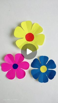 three paper flowers are shown with one being cut out and the other is made from construction paper