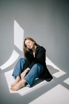 a woman is sitting on the floor with her hands behind her head and looking down