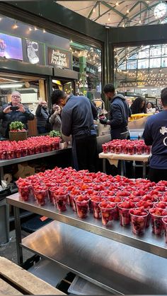 many people are shopping for strawberries at a market place in the city, some with plastic cups on them