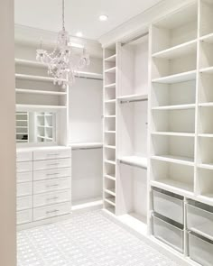 a walk in closet with white shelving and chandelier hanging from the ceiling