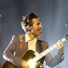 a man holding a guitar and singing into a microphone