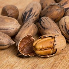 some nuts are sitting on a wooden table and one is open to show the inside