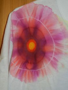 a white shirt with a pink and orange tie dye design on the front that has an orange center in it